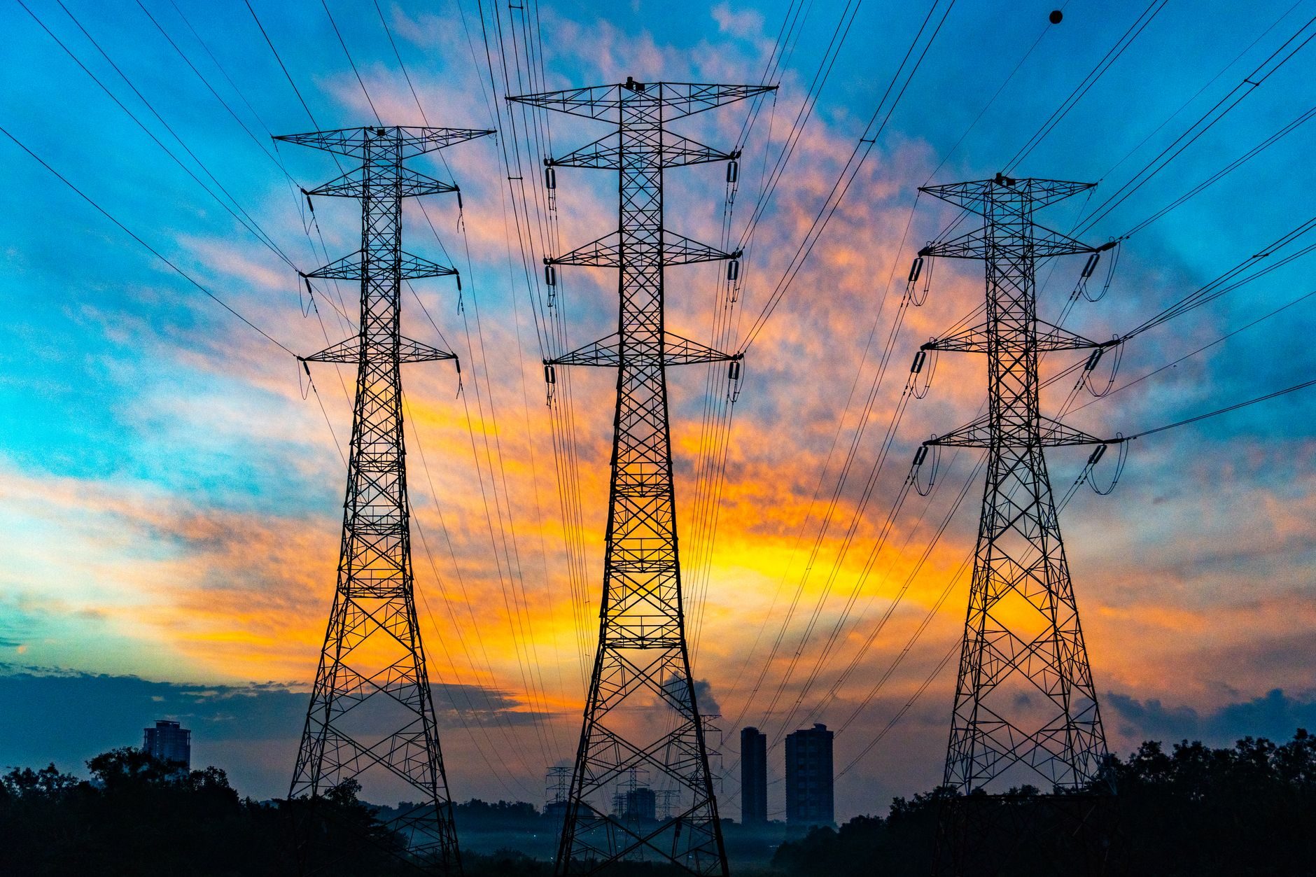 Torri di trasmissione ad alta tensione contro un cielo al tramonto, il vincolo di rete con cui ogni data center si scontra ora